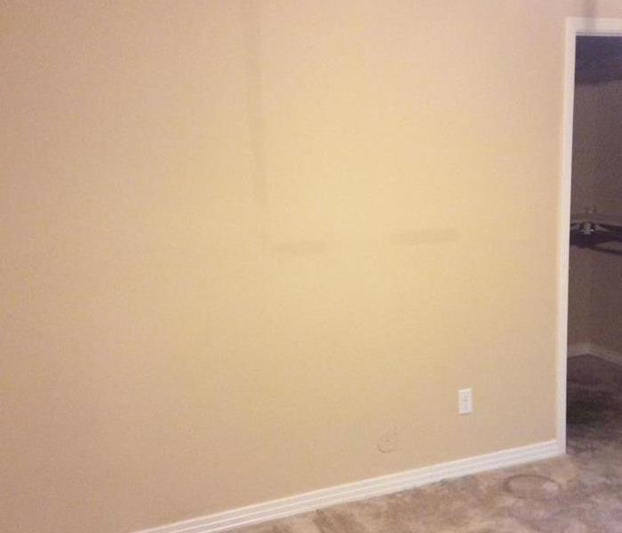 Yellow bedroom with dark water stains on the wall. 
